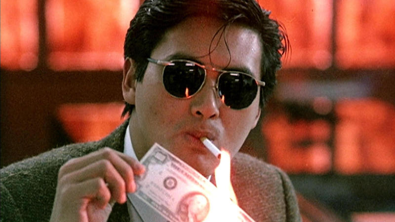 Chow Yun Fat lighting a cigarette with a $100 bill